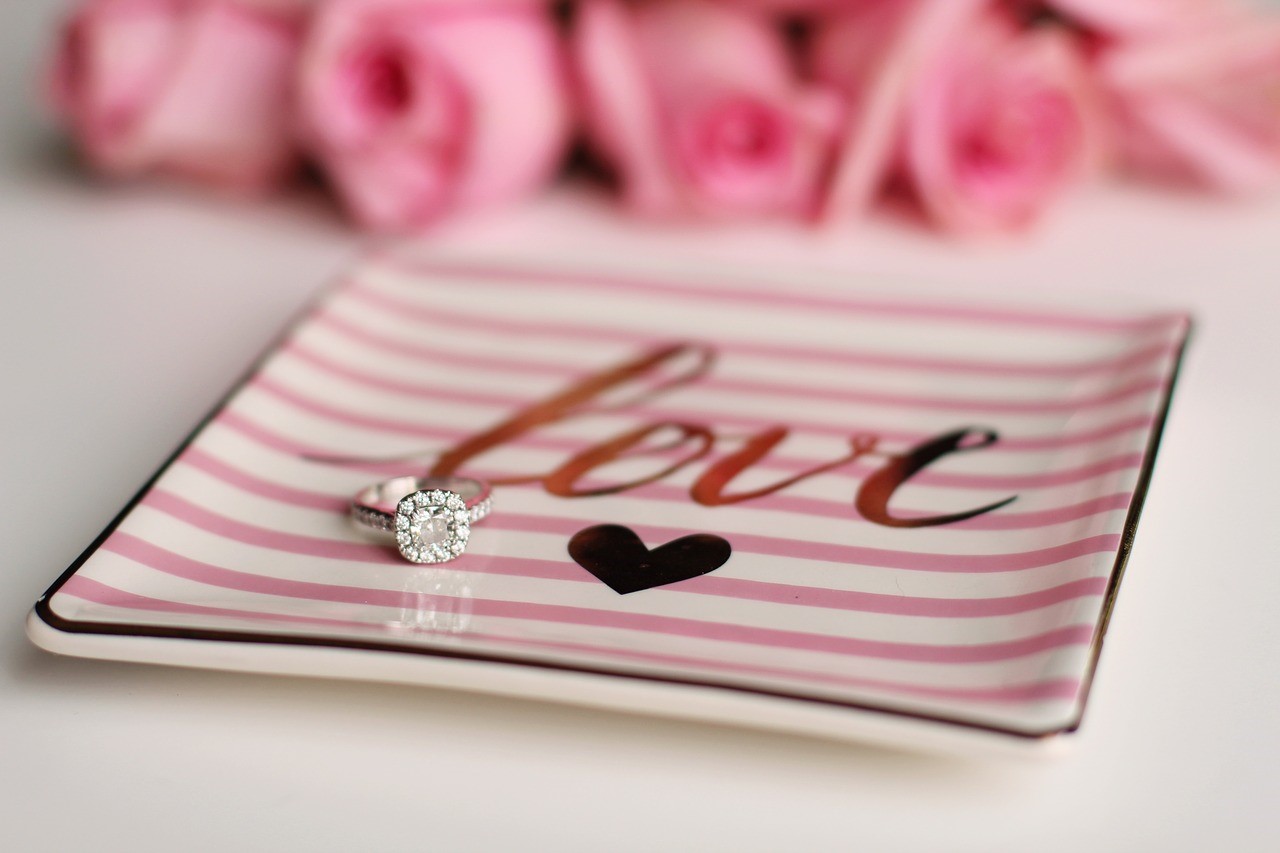 An engagement ring on a pink tray