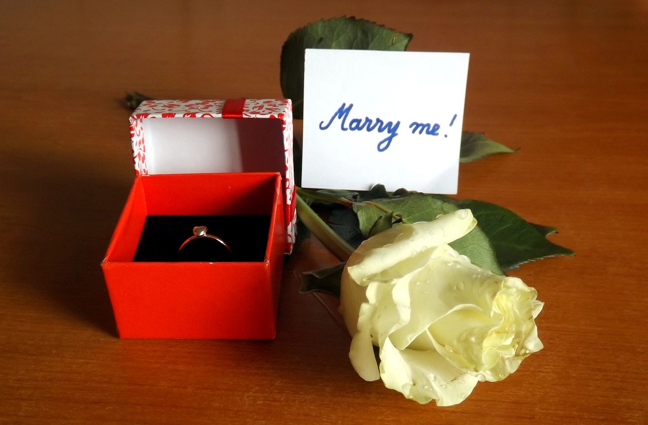 An engagement ring in a box with "Marry Me" message